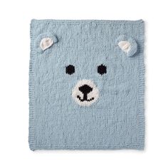 a blue knitted bear rug with black eyes and ears on it's face