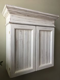 an old white cabinet is hanging on the wall