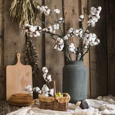 cotton flowers are in a vase next to a cutting board and other items on a table