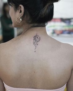 the back of a woman's neck with a small tattoo on her left shoulder