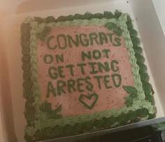 a cake with green frosting that says congrats on not getting arresed