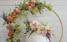 a white cake with pink and green flowers on it's top is surrounded by greenery