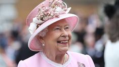 an older woman wearing a pink hat with flowers on it's brim and smiling