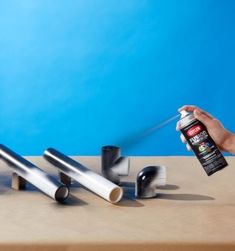 a person is spray painting metal pipes on a table with blue wall in the background