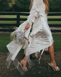 a woman in a white dress is walking down the street with her bouquet and shoes