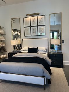 a bedroom with a bed, dresser and two mirrors on the wall above it's headboard