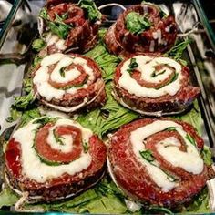 an assortment of sandwiches with meat and cheese on them in a glass dish, ready to be eaten