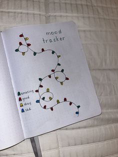 an open notebook with christmas lights on it and the words mood tracker written in green