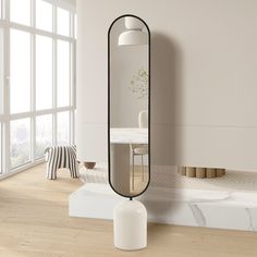 a large mirror sitting on top of a wooden floor next to a white table and chair