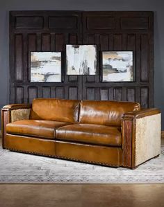 a brown leather couch sitting in front of two framed pictures