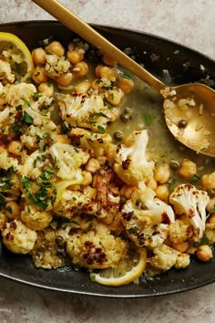 cauliflower and chickpeas in a skillet with a spoon on the side