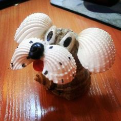 there is a small toy dog made out of seashells on top of a wooden table