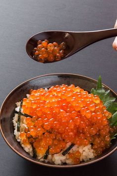 a person is spooning some food out of a bowl with rice and carrots on it