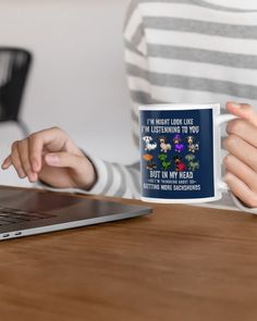 a woman holding a coffee mug in front of her laptop