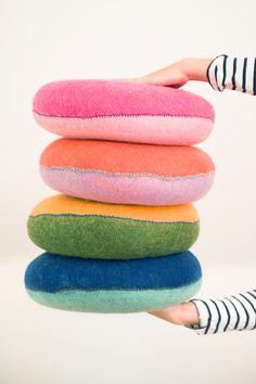 a stack of pillows being held by a woman's hand