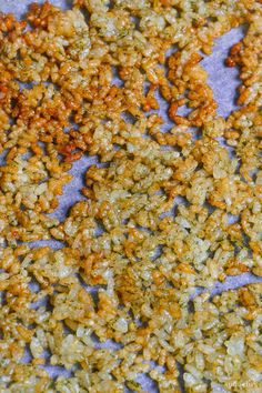 some kind of granola sitting on top of a piece of blue paper with yellow and green flakes