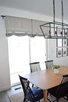 a dining room table and chairs with pictures on the wall above it, along with a potted plant