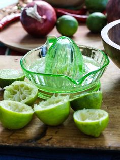 limes cut in half on a cutting board next to an onion bowl and knife