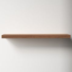 an empty wooden shelf against a white wall