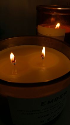 two lit candles sitting inside of a container