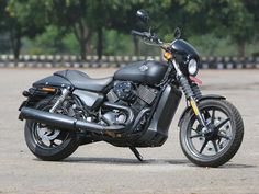 a black motorcycle parked on top of a parking lot with trees in the back ground