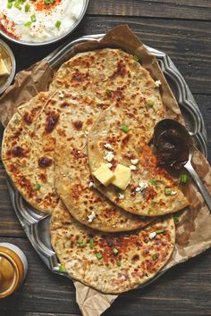 three flatbreads with cheese and green onions on top, sitting on a plate