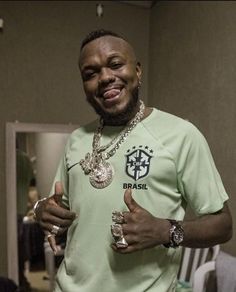 a man in a green shirt is holding two silver rings and giving the thumbs up