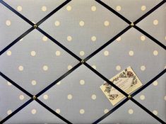 a blue and white polka dot fabric with black leather trimmings is attached to the back of an upholstered wall