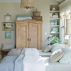 a bedroom with white linens and pillows on the bed in front of a wooden cabinet