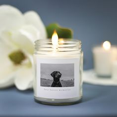 there is a candle with a dog on it next to some white flowers and candles