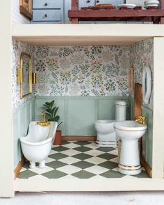 a dollhouse bathroom with two toilets and a potted plant on the counter top