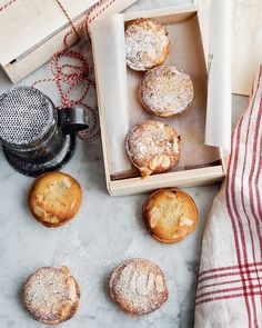 several pastries are sitting in a box next to a tea kettle and napkins