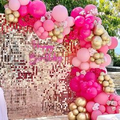 a pink and gold wedding arch decorated with balloons