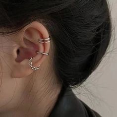 a close up of a person wearing two different types of ear piercings on their ears