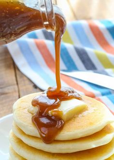 a stack of pancakes with syrup being poured on top