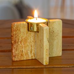 a candle holder made out of marble blocks on a wooden table with a lit candle in the middle