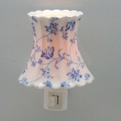 a blue and white flowered glass lamp shade on a light switch plugged into a wall