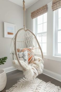 a white hammock hanging from the ceiling in a room with windows and rugs