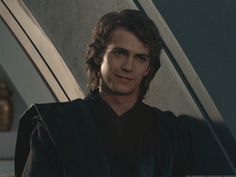 a man with long hair wearing a star wars uniform and smiling at the camera,