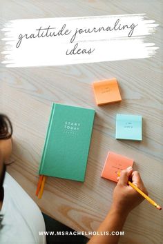 a person writing on a notebook with sticky notes and pencils in front of them