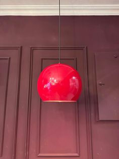 a red light hanging from the ceiling in front of a purple door with two brown doors