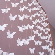 white butterflies are hanging from strings on the wall