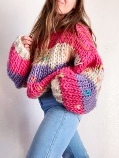 a woman is wearing a colorful sweater and jeans