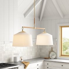 two lamps hanging from the ceiling in a kitchen