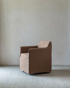 a brown chair sitting on top of a carpeted floor next to a white wall