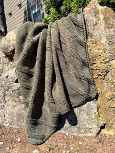 a knitted blanket sitting on top of a rock