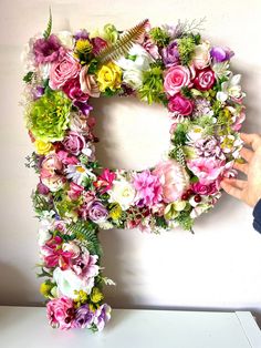 the letter p is made up of flowers and leaves, with one hand reaching for it