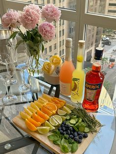 an assortment of fruits and drinks on a table in front of a city street view