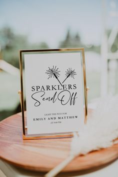 a table with a sign that says sparklers sand - off and a feather on it