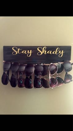 a wooden sign that says stay shady with sunglasses hanging from the bottom and below it